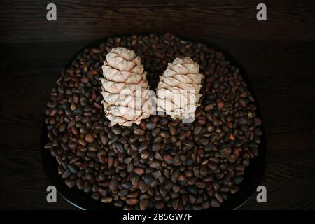 Pine nuts in shells as a background and two whole cedar cones, top view Stock Photo