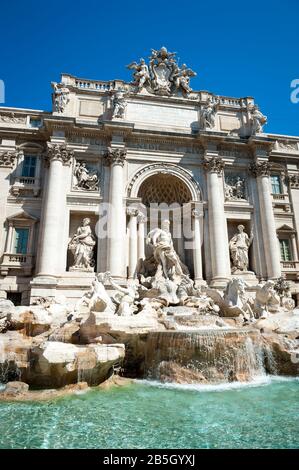 Bright sunny view of Trevi Fountain from the waters of the empty pool under blue sky in Rome, Italy Stock Photo