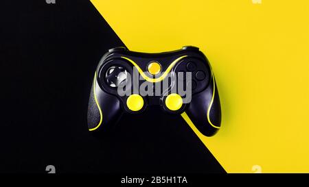 Black gamepad on a black-yellow background, G. Game concept. Device to control and control the game. Video games on PC, console, smartphone. Stock Photo