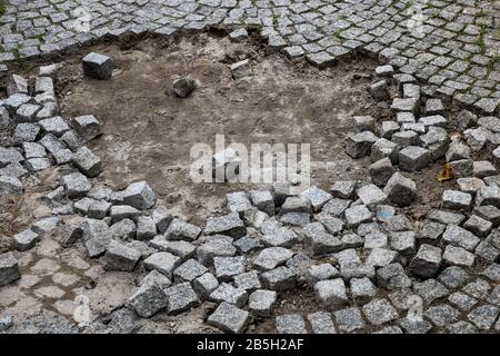 Stone sett sidewalk with hole and visible ground, damaged and in need for repair Stock Photo