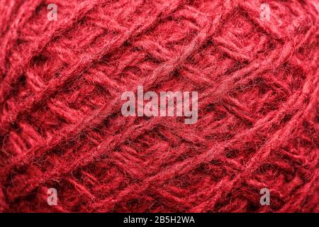 Wool yarn close-up colorful red thread for needlework in macro. Background texture fabric for knitting needle. Full screen wool yarn. Stock Photo