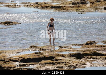 Lady in a bikini on the rocks by Castillo San Sebastian in Cádiz, Spain Stock Photo