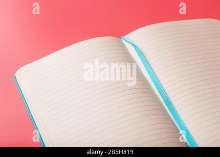 Open a laptop with blank pages on a pink background. Top view, copy space. Elements of notebook sheets with bookmark Stock Photo