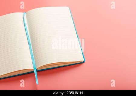 Open a laptop with blank pages on a pink background. Top view, copy space. Elements of notebook sheets with bookmark Stock Photo