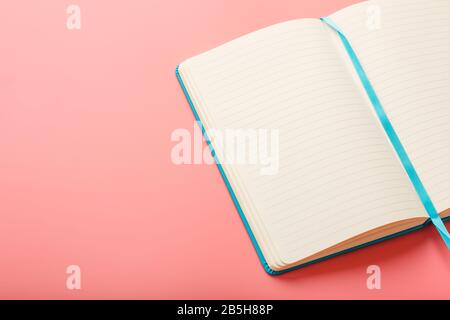 Open a laptop with blank pages on a pink background. Top view, copy space. Elements of notebook sheets with bookmark Stock Photo