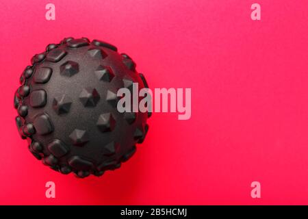 Black lumpy foam body massage ball on red background. For the mechanical and reflex effects on tissues and organs. Stock Photo