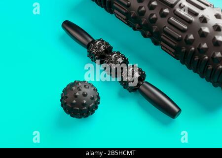 A set of black bumpy foam massage rollers, body rollers, rubber balls on a blue background for mechanical and reflex action on tissues and organs. Stock Photo