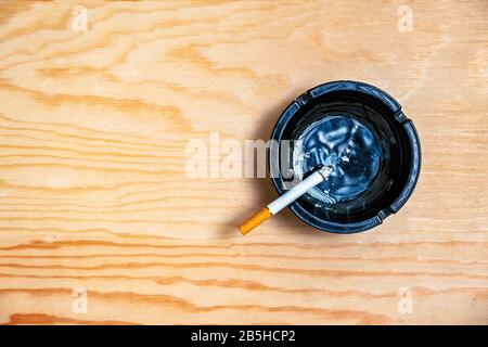 Cigarette in the ashtray on wooden table, addiction concept, overhead view Stock Photo