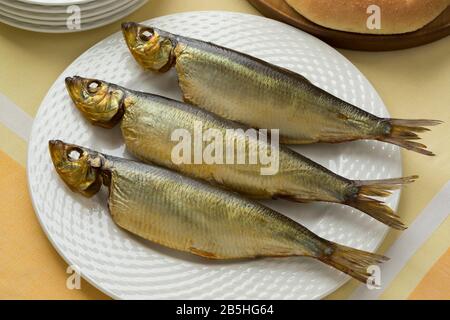 Three whole  Bucklings, hot smoked herring on a dish for a meal close up Stock Photo