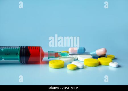 A pile of medical pills of different colors on a blue background. Healthcare and medicine concept. Stock Photo