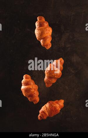 Croissants flying on dark background. Levitation scene. Stock Photo