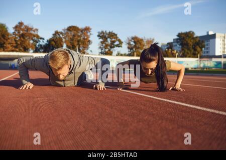 Young couple doing pushups in the stadium in the morning. Sport lifestyle. Stock Photo