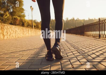 Rear view of a runner walking on a road in a park at dawn in summer in autumn. Stock Photo