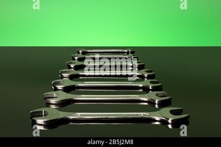 Set of wrenches on a green background. Mirror surface. Stock Photo