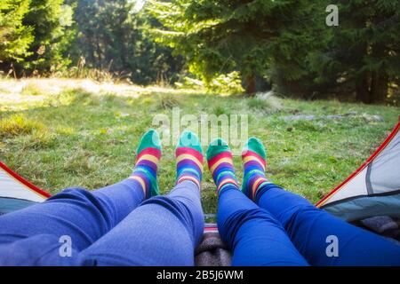 View from inside with couple of legs inside camping tent - Travel wanderlust concept with young people enjoying adventure experience.  Concept about t Stock Photo