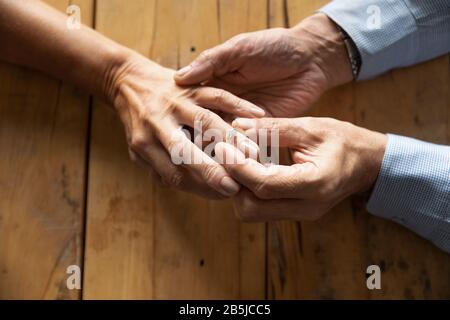 Old man put wedding ring on middle-aged woman hand Stock Photo