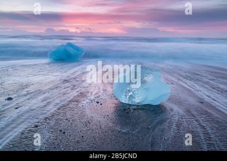 Beautiful sunset over famous Diamond beach, Iceland. This sand lava beach is full of many giant ice gems, placed near glacier lagoon Jokulsarlon Ice Stock Photo