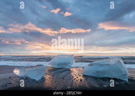 Beautiful sunset over famous Diamond beach, Iceland. This sand lava beach is full of many giant ice gems, placed near glacier lagoon Jokulsarlon Ice Stock Photo