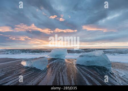 Beautiful sunset over famous Diamond beach, Iceland. This sand lava beach is full of many giant ice gems, placed near glacier lagoon Jokulsarlon Ice Stock Photo