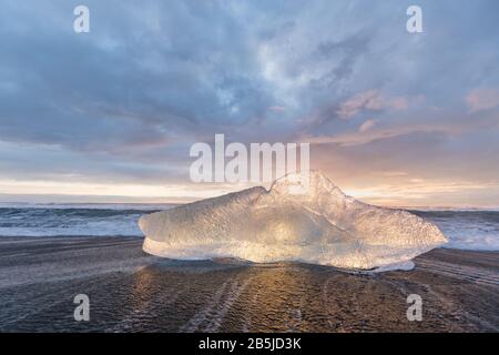 Beautiful sunset over famous Diamond beach, Iceland. This sand lava beach is full of many giant ice gems, placed near glacier lagoon Jokulsarlon Ice Stock Photo