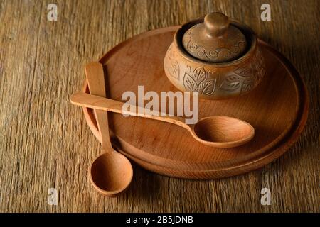 Wooden spoon, plate, clay pot on old table. Copy space Stock Photo