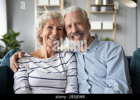 Portrait of happy old couple hug relaxing on couch Stock Photo