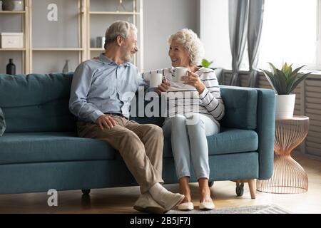 Happy mature couple relax on couch drinking tea Stock Photo