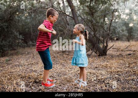 Two kids playing and dancing in the forest Stock Photo