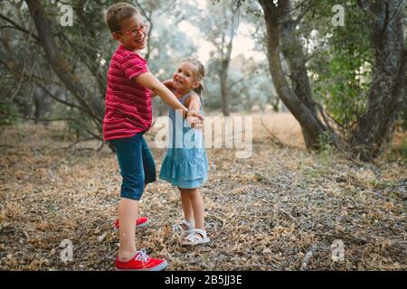 Two kids playing and dancing in the forest Stock Photo