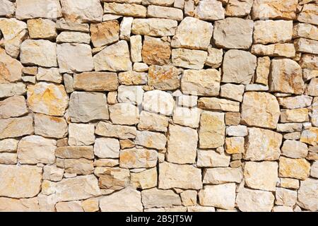 Masonry wall of stones with irregular pattern texture background Stock Photo