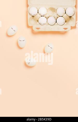Festive Easter peach color background with white eggs and eyes drawn on them. The inscription is a happy Easter. Stock Photo