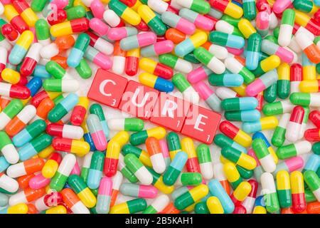 Mass of colourful pills / gelatine capsules & CURE in letter tiles. For NHS, big pharma, Medicare, Medicaid, illness cured, coronavirus cure, Covid-19