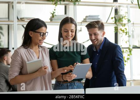 Multiethnic coworkers discuss ideas in office using tablet Stock Photo