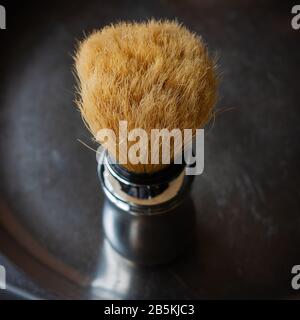 Shaving brush on the rustic black background, top view in chiroscuro style. Skin care for men. Place for text, square format. Stock Photo