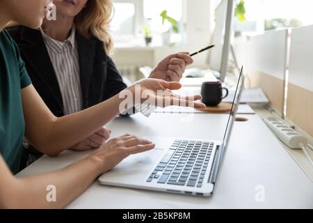 Female coworkers cooperate discussing ideas using laptop Stock Photo