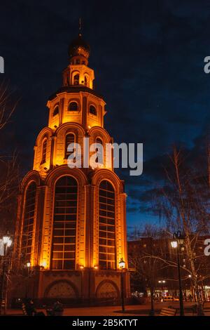 The bell tower well highlighted by city flashlights. A Venus planet above a bell tower shining through the clouds. In Krivoy Rog, Ukraine Stock Photo