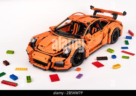 Different views of assembled orange lego Porsche GT 3RS car surrounded by spare lego bricks Stock Photo