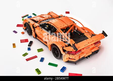 Different views of assembled orange lego Porsche GT 3RS car surrounded by spare lego bricks Stock Photo