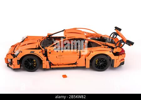 Different views of assembled orange lego Porsche GT 3RS car with one spare leftover lego brick Stock Photo