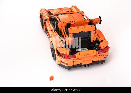 Different views of assembled orange lego Porsche GT 3RS car with one spare leftover lego brick Stock Photo