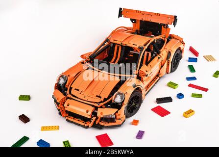 Different views of assembled orange lego Porsche GT 3RS car surrounded by spare lego bricks Stock Photo