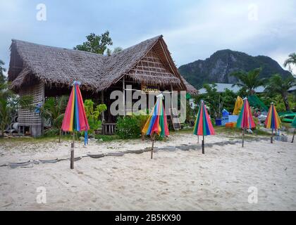 Thai massage shop on empty white sand beach with closed multicolored beach umbrellas Stock Photo