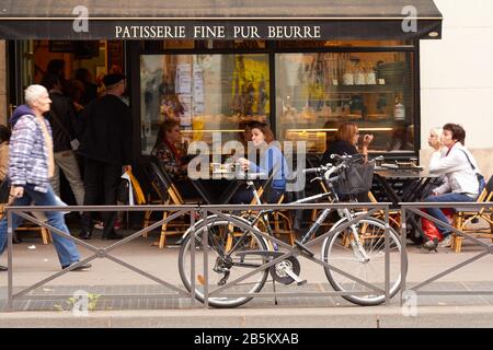 People sitting outside eating and people queuing to enter popular Patisserie restaurant in Paris Stock Photo