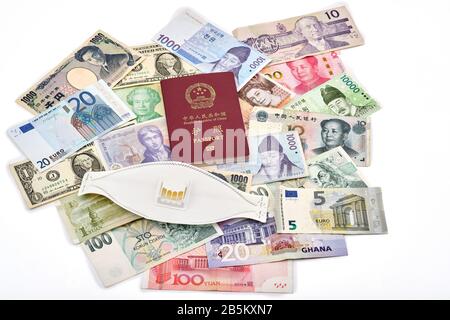 East meets west travel concept with Chinese passport, mixture of western and asian currencies and corona virus face mask for safe travelling