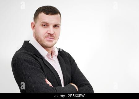 Portrait of an elegant young businessman standing with arms crossed over grey background Stock Photo