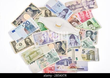 Travel safely around the world concept with corona virus face mask, and mixture of western and asian currencies Stock Photo