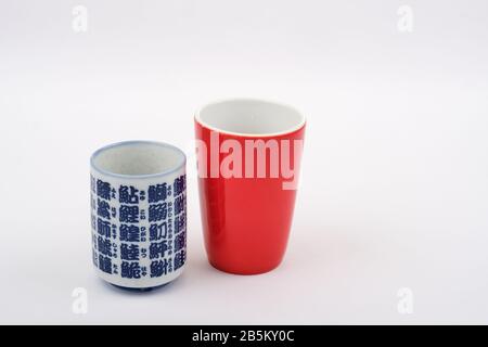 East meets west travel concept with red traditional western tea coffee mug and blue white japanese tea cup with japanese writing Stock Photo