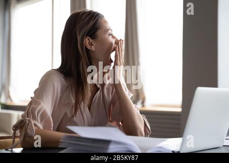 Distracted from work study young woman yawning. Stock Photo