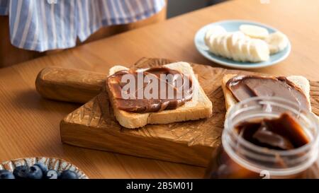 Chocolate nut butter toast on a wooden board. Tasty breakfast or lunch sandwich Stock Photo