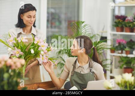 Portrait of two smiling female florists discussing bouquets while working in flower shop Stock Photo